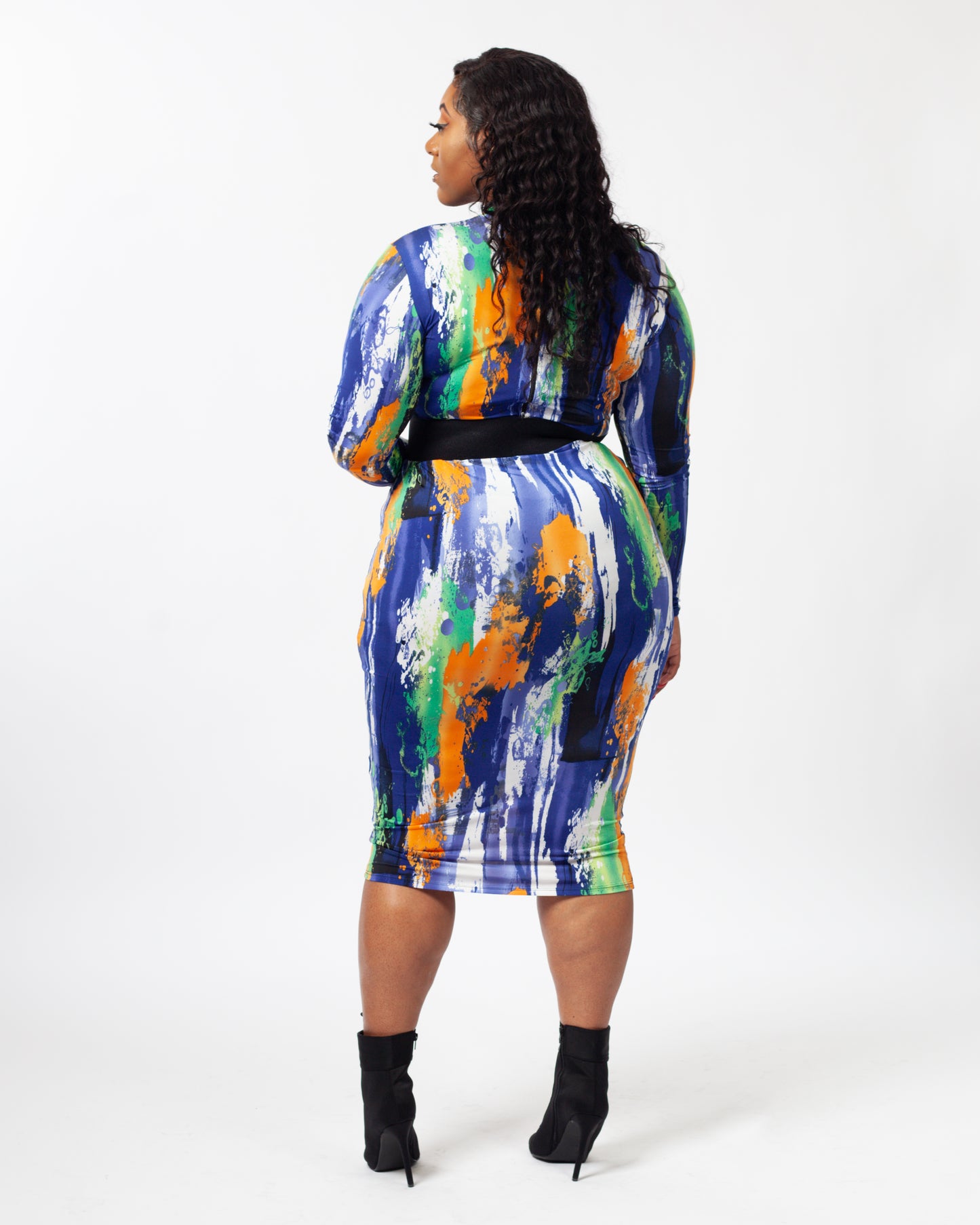 A model wearing a long sleeve multicolor midi dress with a belt as an accessory.