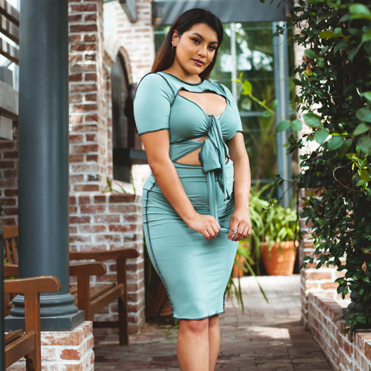 A model wearing a double front tie midi dress with plants in the background