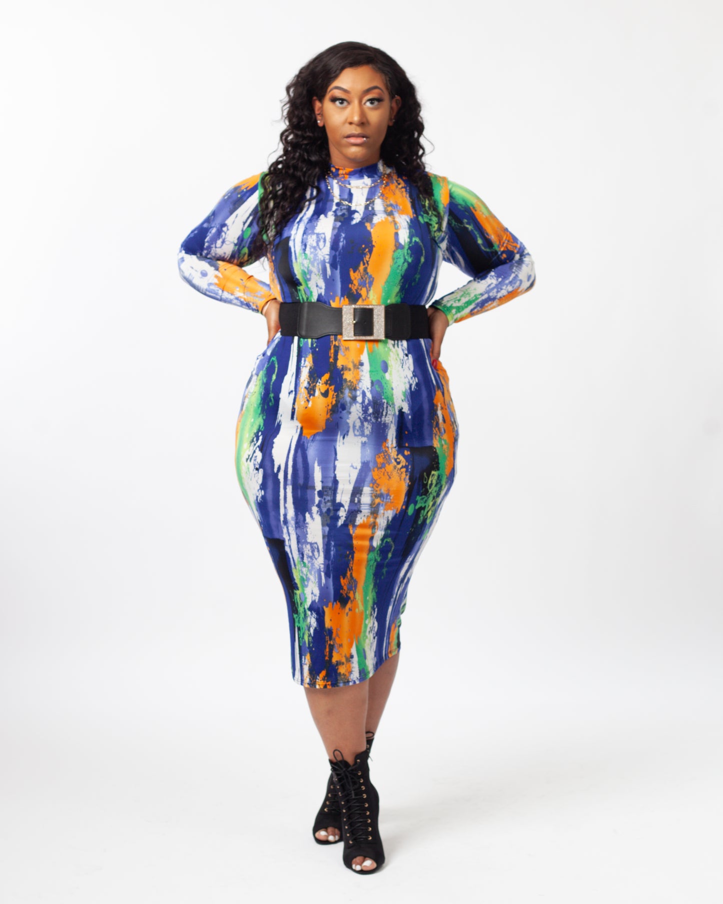 A model wearing a long sleeve multicolor midi dress with a belt as an accessory. 
